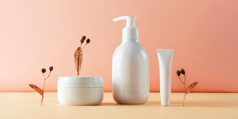 Various cosmetic bottles and natural plant parts creative still life beauty photography. Lotion, moisture cream and lip balm blank empty mockup. Trendy composition